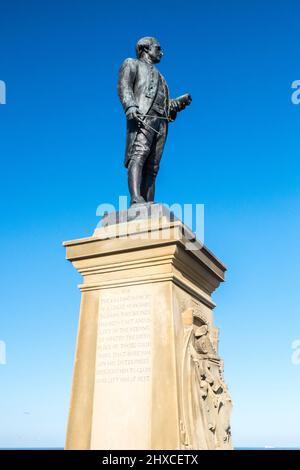 Captain Cook Statue,Cook Statue,near,Whalebone Arch,with,views,along,Esplanade Crescent,West Cliff,coast,coastline,seafront,headland,of,this,popular,tourist,attraction,seaside,beach,resort,of,Whitby,Borough of Scarborough,near,Scarborough,  North,North Yorkshire,Whitby,Yorkshire,England,English,UK,United Kingdom,GB,Great Brtiain,British,Europe, Stock Photo