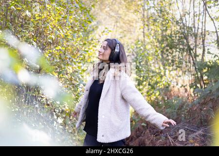 Young woman with headphones dancing to music in forest Stock Photo