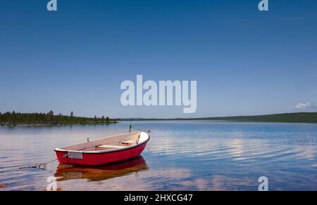 Red rowing boat on the shore of a lake in Scandianvia Stock Photo