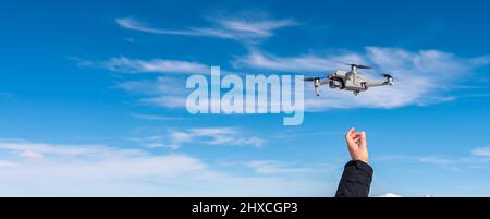 Drone landing on male hand against blue sky background Stock Photo