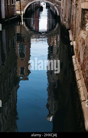 Single gondola traveling down a small deserted canal in Venice, Italy Stock Photo