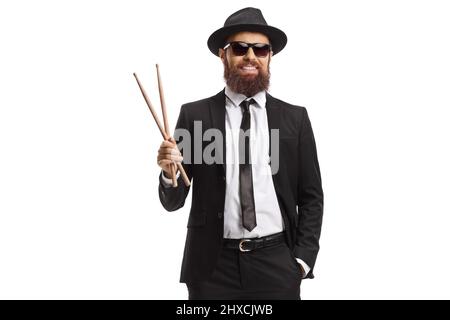 Man in a black suit holding a pair of drumsticks isolated on white background Stock Photo