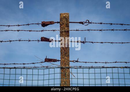 rusty barbed wire fence with blue sky background Stock Photo