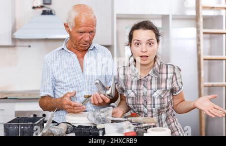 Woman and elderly father discussing installing faucet Stock Photo