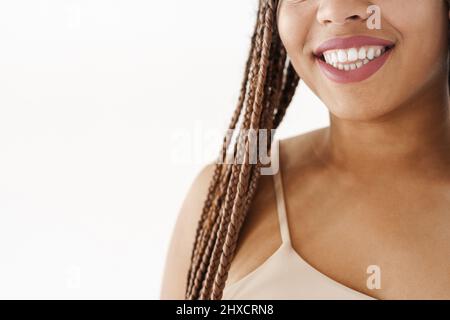 Smiling young african woman with dreadlocks over white wall background cropped image Stock Photo