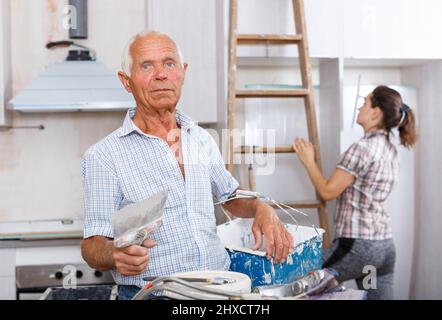 Old worker with plastering tools Stock Photo