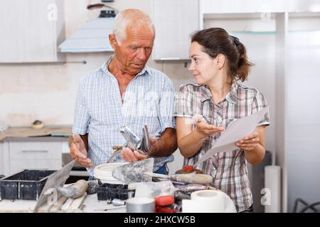 Confused woman with elderly father reading work manual on mixer tap Stock Photo