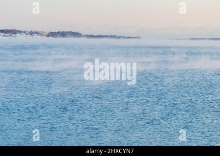 Minimal view of the sea from Helsinki coastline. The weather is so cold that the water freezes and crates a light mist on its surface Stock Photo