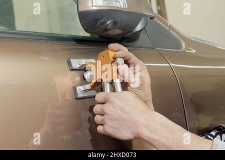 The hands of a professional painter repairing dents without painting. Stock Photo