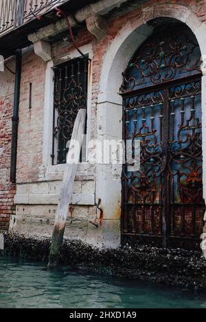 Barred door directly on the canal in the old town of Venice, Italy Stock Photo