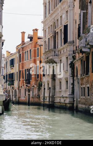 Venetian gondola traveling on a small canal in Venice, Italy Stock Photo