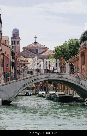 Small canal with Venetian bridge overlooking Chiesa di San Nicola da Tolentino and Giardini Papadopoli in Santa Croce neighborhood in Venice, Italy. Stock Photo