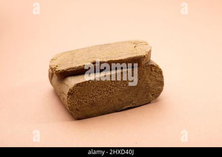 hashish tablet cut out next to large 100 gram portion, brown background Stock Photo