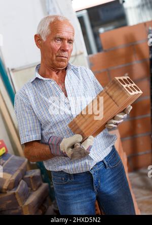 Man inspecting brick for installing wall Stock Photo