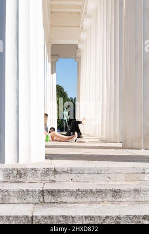 view through the columns of Theseus temple in Volksgarten park with young people taking a rest, Vienna, Austria Stock Photo