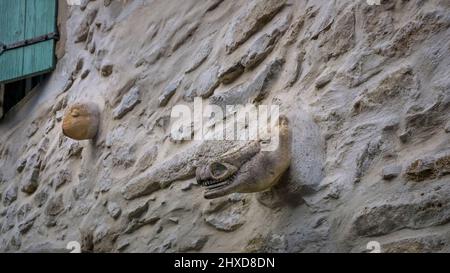 Masquen on stone wall in Aigne. The old village center has the shape of a snail shell and was built in the 11th century. Stock Photo