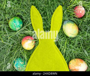 Green felt rabbit with colored eggs. Easter. Copy space Stock Photo