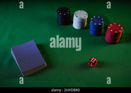 Playing cards, poker chips and a dice on a green table. Game table for leisure. View from above. Stock Photo