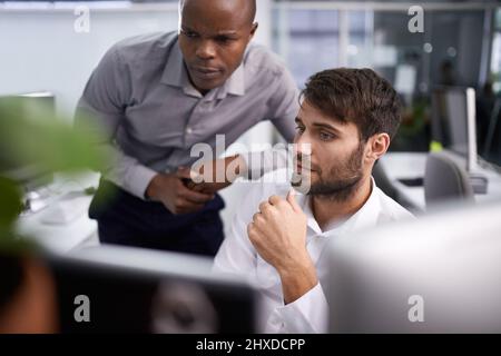 Success through technology. Shot of two businessmen looking at a computer. Stock Photo