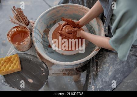 Clay artist modeling product on potter wheel in workshop Stock Photo