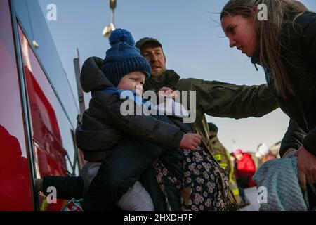 Medyka, Poland. 11th Mar, 2022. Ukrainian refugee family with a child queuing to board on a coach that takes refugees to Przemysl. Ukrainian refugees at Medyka border crossing on the 16th day of Russian invasion in Ukraine. Credit: SOPA Images Limited/Alamy Live News Stock Photo