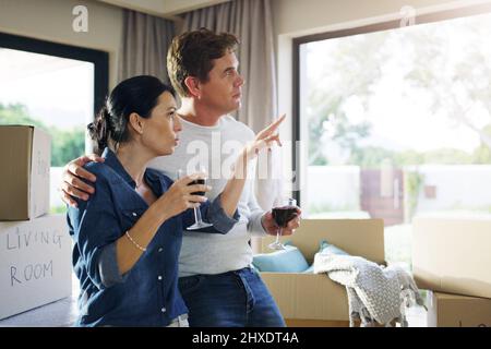 And now to give our home a heart. Shot of a young couple drinking wine together while taking a break from unpacking. Stock Photo