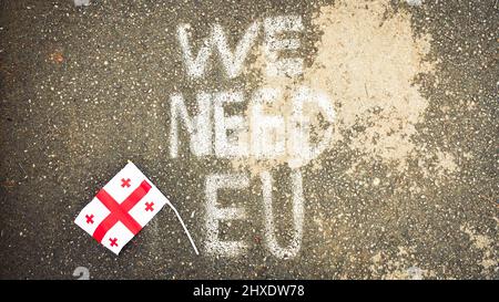 Georgian flag lay on ground by written statement 'we need EU'. Integration process to EU concept Stock Photo