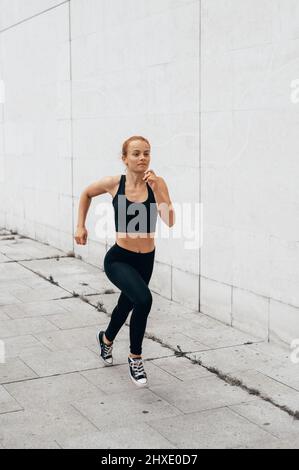 Young woman in black sportswear running through the city. vertical photo for social networks Stock Photo