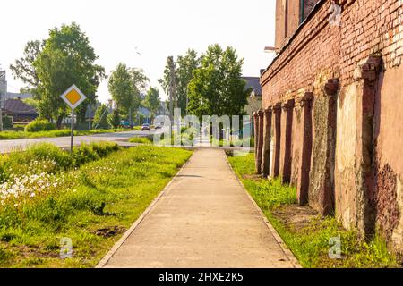 street of a small settlement with individual buildings and a brick structure along the sidewalk, selective focus Stock Photo