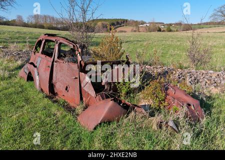 Derelict and rusty antique Vintage Car in a Farm Field on a Sunny Day Stock Photo