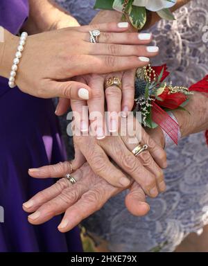 Four hands placed on top of each other palms up, unity of parents