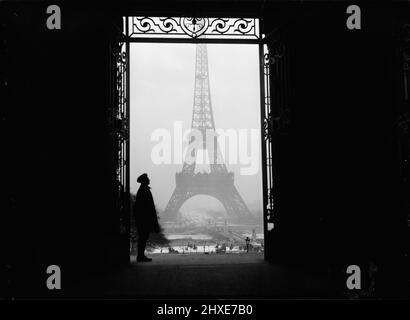Vintage 1919 black and white photograph of the Eiffel tower framed by a doorway with a person standing in it, Paris, France Stock Photo