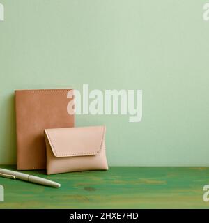Note, pen, card wallet on wooden desk. green wall background Stock Photo