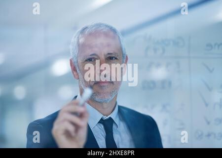 His calculations for success are all adding up. Cropped shot of a mature businessman writing figures on a glass screen. Stock Photo