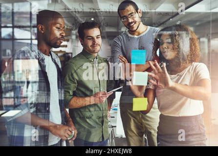 Their success is based on teamwork. Cropped shot of a group of young designers planning on a glass board. Stock Photo