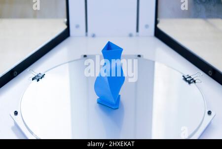 Bright blue object printed by 3d printer on 3d printer inside. Stock Photo