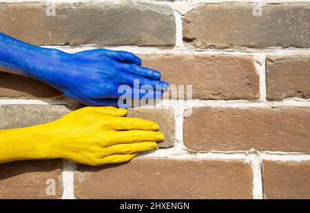 female hands are painted in the colors of the Ukrainian flag on the background of a brick wall. willingness to fight for freedom and national independ Stock Photo