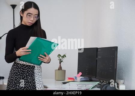 Young asian broker using the computer to analyze cryptocurrency exchange market. Stock Photo