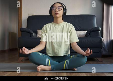 Young asian woman listening relaxing music and meditating doing the easy pose. Stock Photo