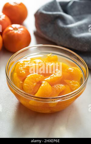 Canned tangerine. Pickled mandarin fruit in the bowl on kitchen table. Stock Photo
