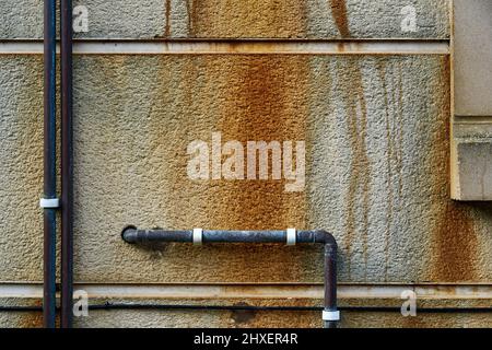 Rust and pipes on a concrete wall Stock Photo