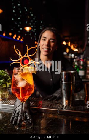 The young Latin brunette prepares a cocktail at the bar counter. job waitress profession Stock Photo