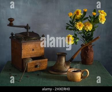 Still life with a bouquet of flowers, a cup of coffee and an old coffee grinder. Vintage. Stock Photo