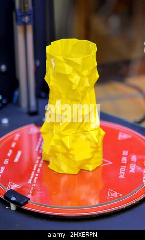 The object in the form of a yellow vase stands on the desktop of a three-axis 3d printer Stock Photo