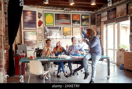 Group of young cheerful employees is having fun while working in a relaxed atmosphere in the office together Stock Photo