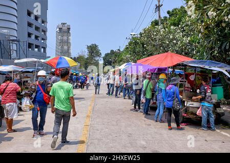 Thailand construction workers taking their lunch break and buying from food carts in the adjoining street. Thailand Southeast Asia Stock Photo