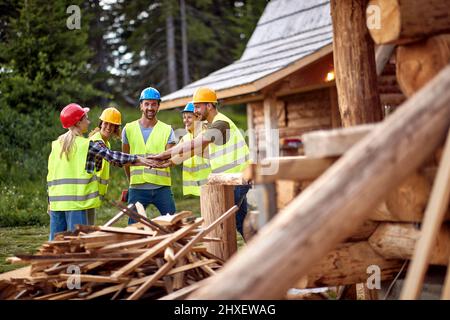 Teamwork young construction workers.Construction workers together working on wooden house, Stock Photo