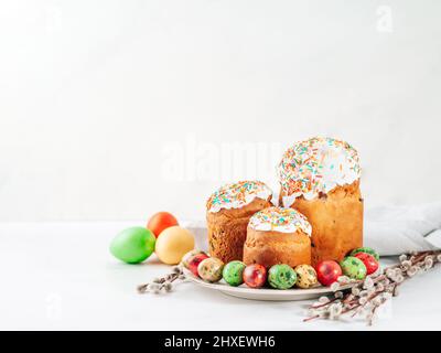 Traditional Russian Ukrainian Easter Cake Kulich. Orthodox Christian Easter Bread or Easter Cake with frosting, Easter Eggs and willow twigs on white marble background. Copy space for text or design Stock Photo