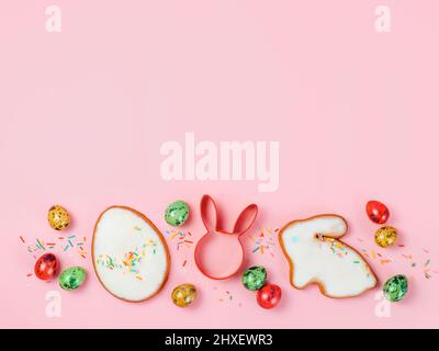 Easter cooking baking concept. Easter cookie cutter on pink pastel background. Happy Easter Day concept. Easter cookie cutters and cookies, colorful eggs over pink background. Copy space for text. Top view or flat lay Stock Photo