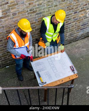A construction worker and supervisor studying the building plan. Stock Photo